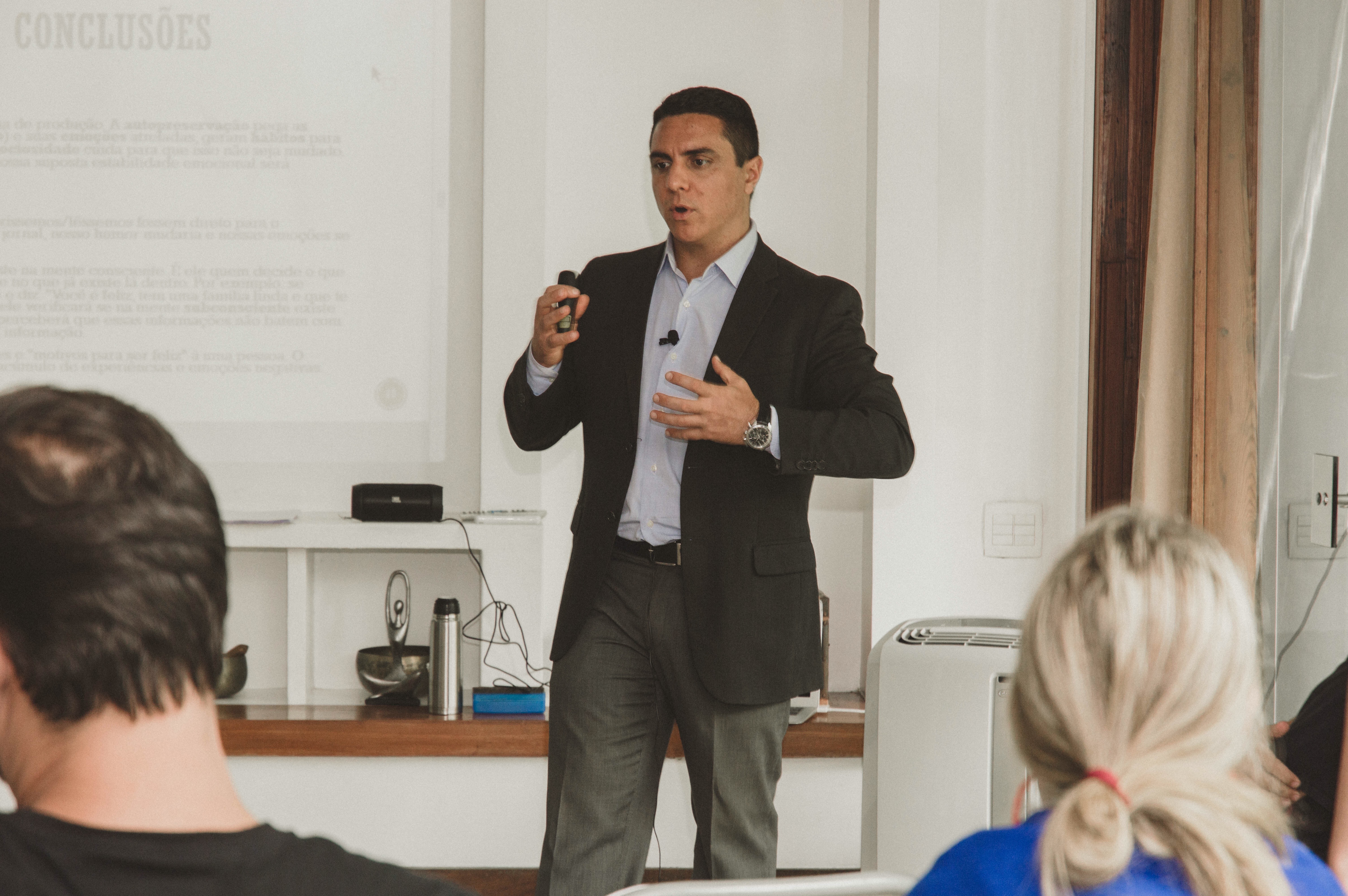 Daniel Strucchi em aula, falando ao microfone diante de uma turma